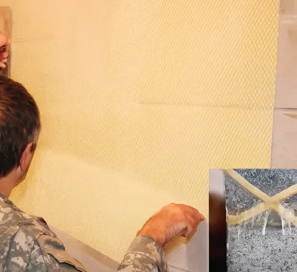Soldier applies ballistic Kevlar wall covering for blast protection and reinforcement testing.